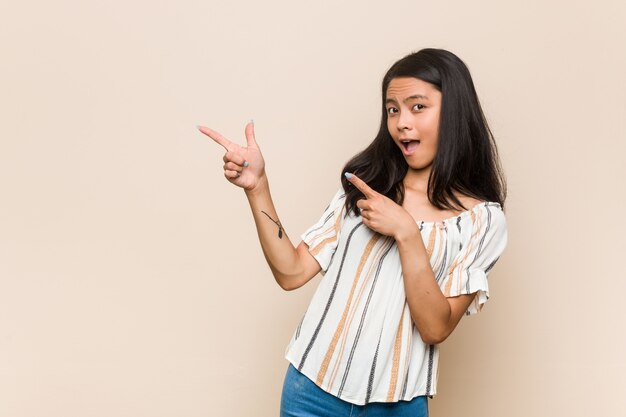 Junge nette chinesische Jugendlichfrau gegen eine rosa Wand