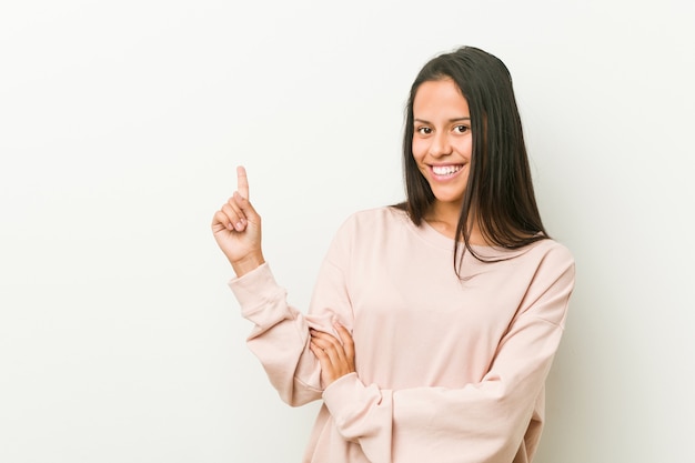 Junge nette hispanische Jugendlichfrau, die mit dem Zeigefinger weg nett zeigen lächelt.