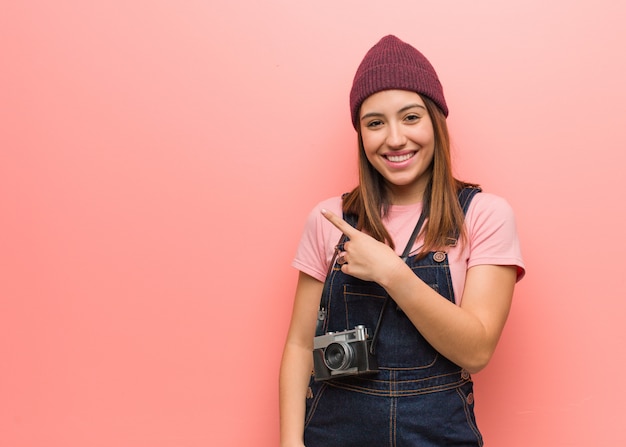 Junge niedliche Fotograffrau, die lächelt und zur Seite zeigt