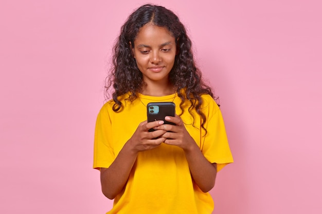 Junge, optimistische indische Frau benutzt das Telefon, um mit Freunden zu plaudern, steht im Studio