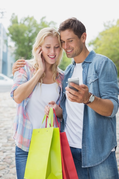 Junge Paare der Hüfte, die Smartphone auf Einkaufsreise betrachten
