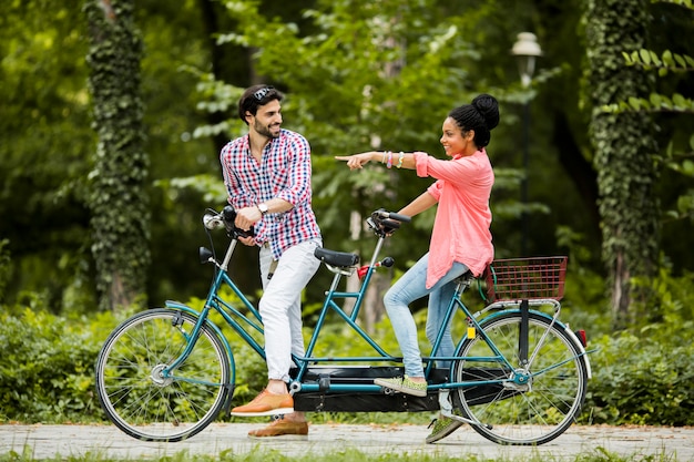 Junge Paare, die auf das Tandemfahrrad fahren