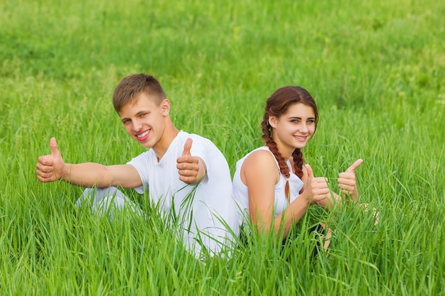 Junge Paare, die auf einer grünen Wiese sitzen