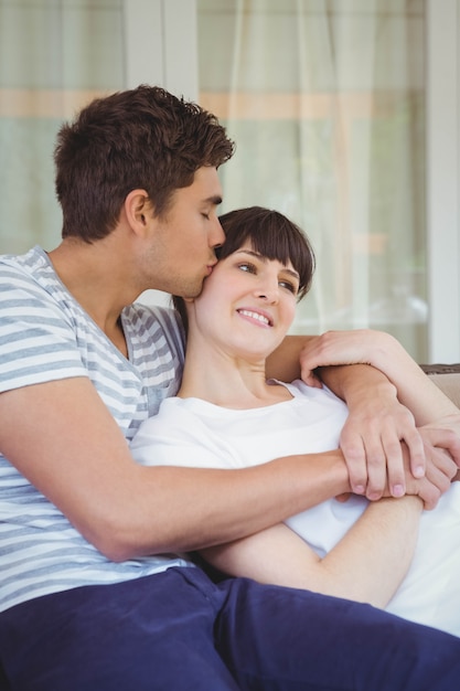 Junge Paare, die auf Sofa im Wohnzimmer streicheln