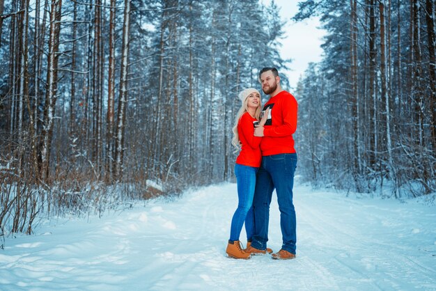 Junge Paare, die im Winterwald umfassen. Winterurlaub