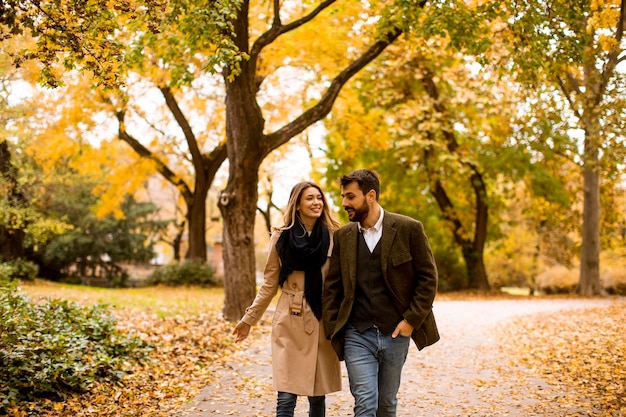 Junge Paare, die in den Herbstpark gehen