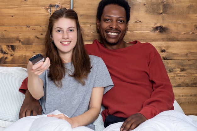 Junge Paare, die in einem Bett fernsehen