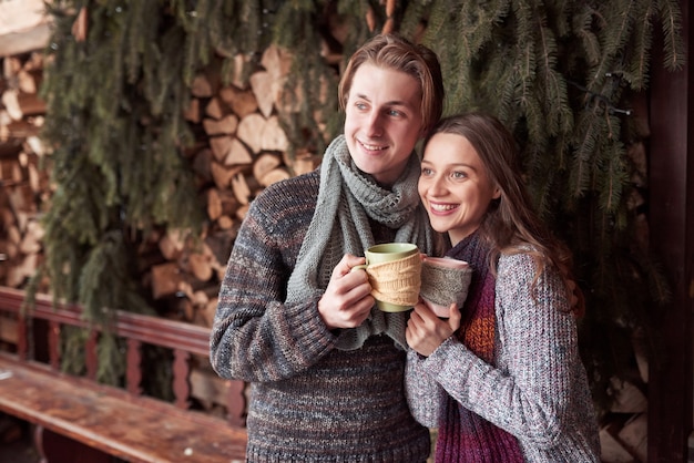 Junge Paare, die in einer romantischen Kabine draußen im Winter frühstücken. Winterurlaub und Ferien. Weihnachtspaare des glücklichen Mannes und der Frau trinken heißen Wein. Verliebtes Pärchen