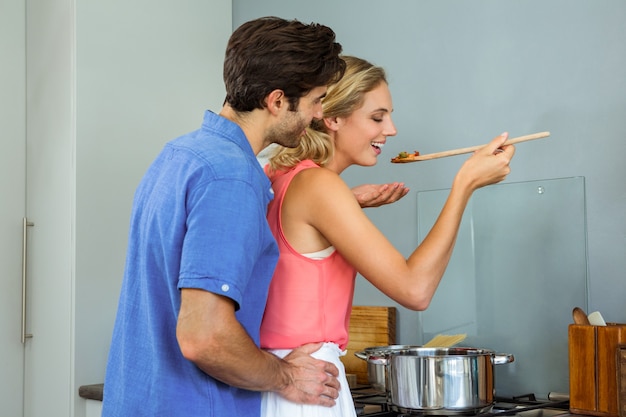 Junge Paare, die zu Hause Mahlzeit in der Küche schmecken