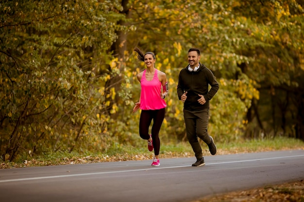 Junge Paare, die zusammen im Herbstpark joggen