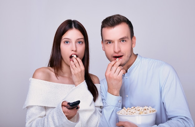 Junge paare, die zusammen stehen, film aufpassen und popcorn essen.