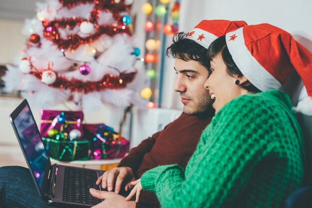 Junge Paare mit Laptop während der Weihnachtszeit