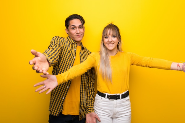 Junge Paare über dem vibrierenden gelben Hintergrund, der sich präsentiert und einlädt, um zu kommen