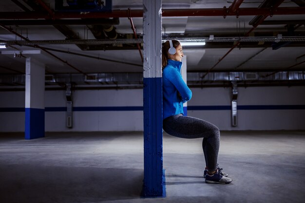 Junge passen kaukasische Sportlerin im Trainingsanzug, der schnell in der Garage läuft.