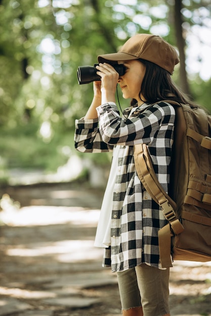 Junge Pfadfinderin, die Parks mit Rucksack und Fernglas erkundet