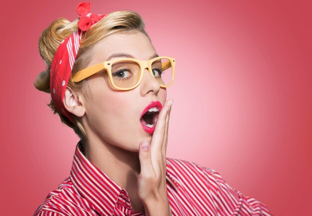 Junge Pin-up-Blondine mit Brille mit schockiertem Ausdruck