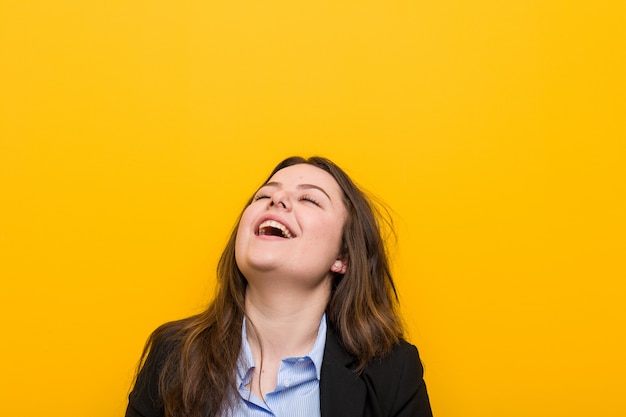 Junge plus die kaukasische Geschäftsfrau der Größe entspannten sich und das glückliche Lachen, der ausgedehnte Hals, der Zähne zeigt.