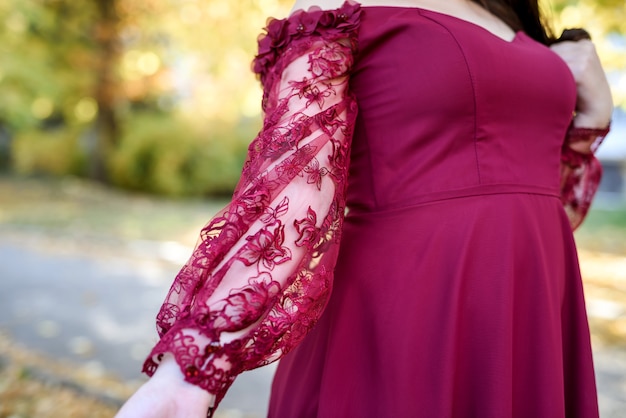 Junge Prinzessin in einem schönen roten Kleid im Park. Der Hintergrund ist helle, goldene Herbstnatur.