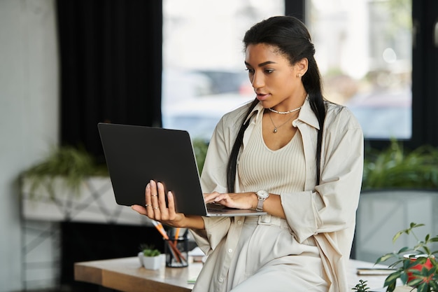Junge professionelle Frau arbeitet intensiv an ihrem Laptop in einer modernen Büroumgebung mit Pflanzen