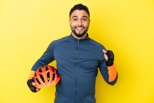 Junge Radfahrer arabischer Mann isoliert auf gelbem Hintergrund feiert einen Sieg in Siegerposition