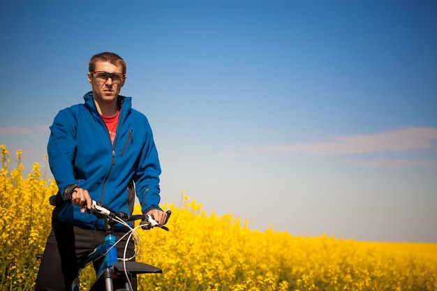 Junge Radfahrer fährt im Frühjahr Rapsfeld mit dem Mountainbike