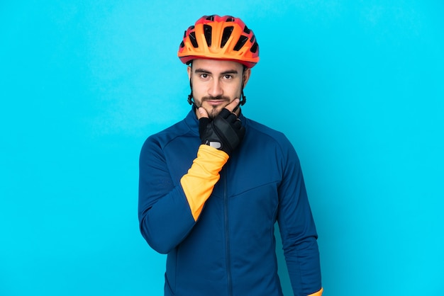 Junge Radfahrer Mann isoliert auf blauem Hintergrund denken