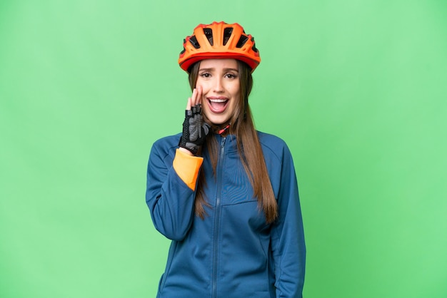 Junge Radfahrerin vor isoliertem Chroma-Key-Hintergrund mit überraschtem und schockiertem Gesichtsausdruck