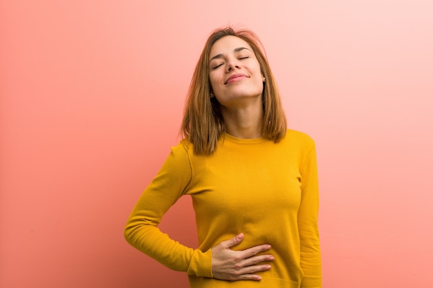 Junge recht junge Frau berührt Bauch, lächelt leicht und isst und Zufriedenheitskonzept.