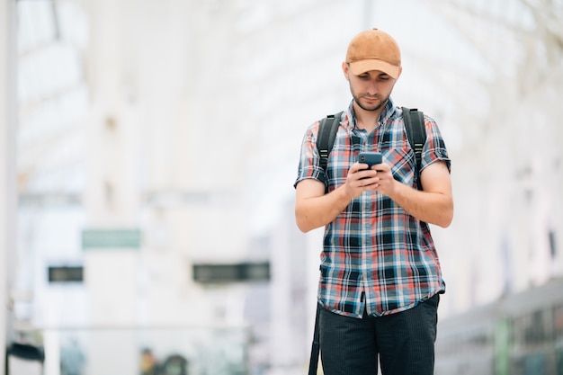 Junge Reisende am Bahnhof mit Telefon im Bahnhof