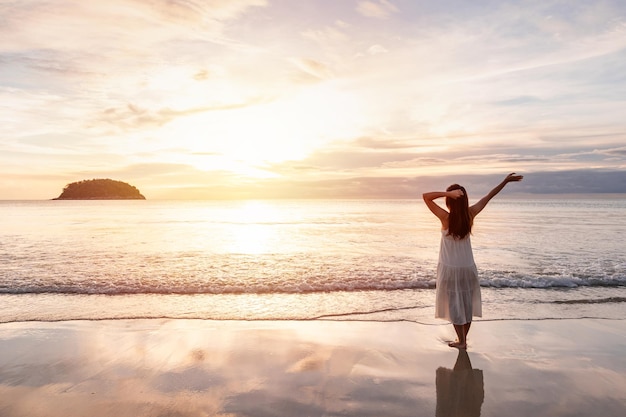 Junge Reisende, die zu Fuß gehen und den wunderschönen Sonnenuntergang am ruhigen Strand genießen Reisen Sie im Sommerurlaubskonzept