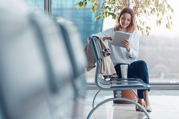 Junge reisende Frau mit einem Tablet in der Abflughalle am Flughafen