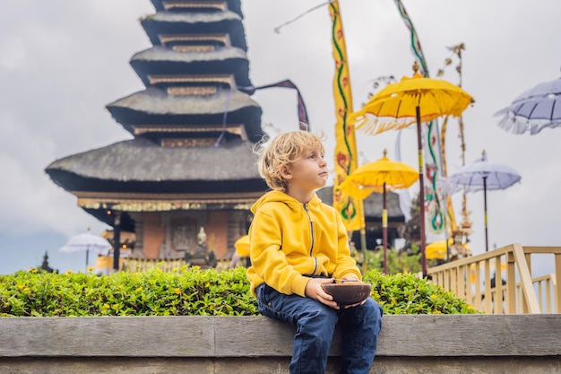 Junge Reisende im Hintergrund des hinduistischen Tempels Pura Ulun Danu Bratan Bali, umgeben von Blumen an