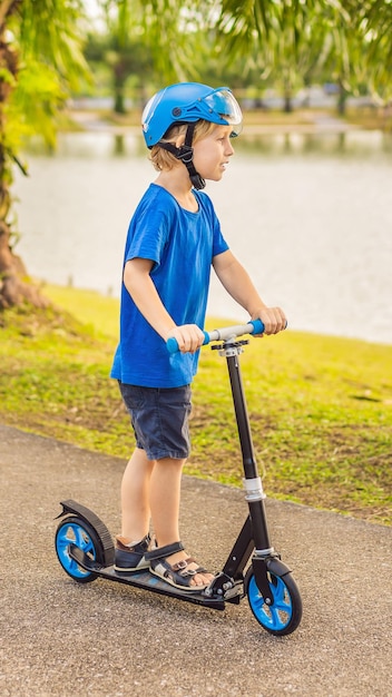 Junge Reiten Roller im Freien im Park Sommerzeit Kinder spielen gerne im Hochformat im Freien