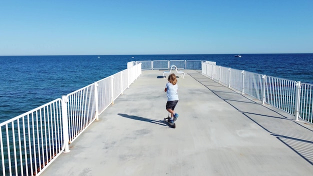 Junge reitet Roller auf einem Pier am Sonntag