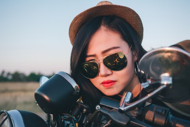 Junge reizvolle Frau auf einem Motorrad in der Natur auf dem Sonnenuntergang. Reisekonzept.