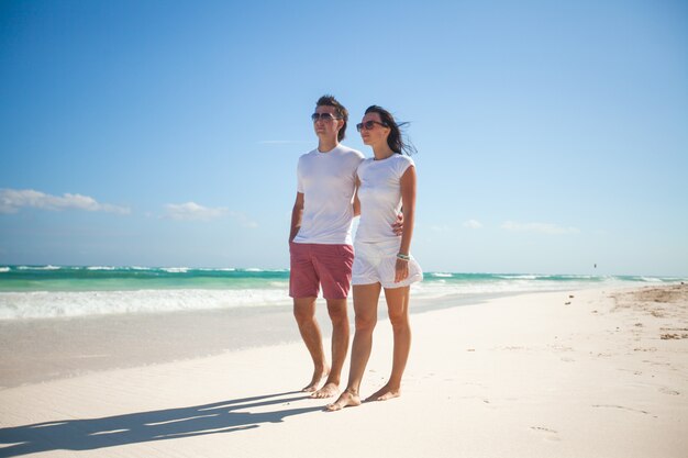 Junge romantische Paare, die auf exotischen Strand am sonnigen Tag gehen