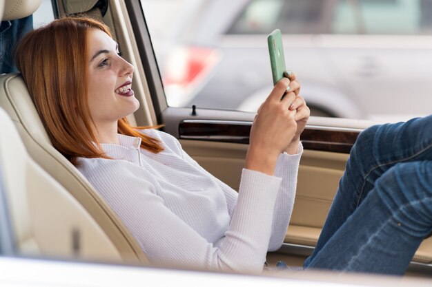 Junge rothaarige Fahrerin, die Selfies mit ihrem Handy nimmt