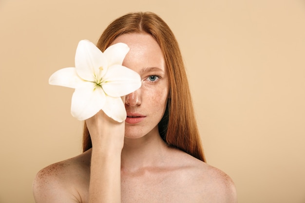 Junge rothaarige frau, die blume hält.