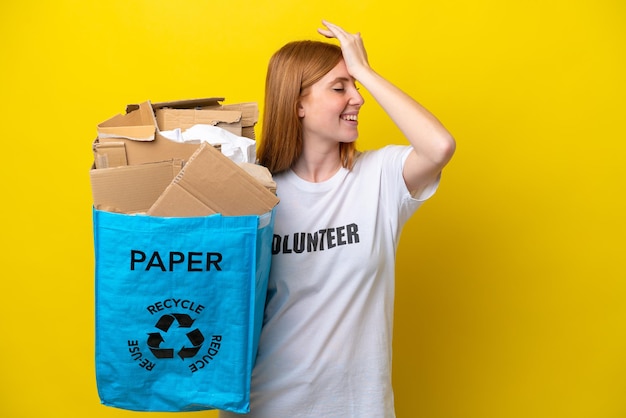 Junge rothaarige Frau, die einen Recycling-Beutel voller Papier hält, um isoliert auf gelbem Hintergrund zu recyceln, hat etwas erkannt und die Lösung beabsichtigt