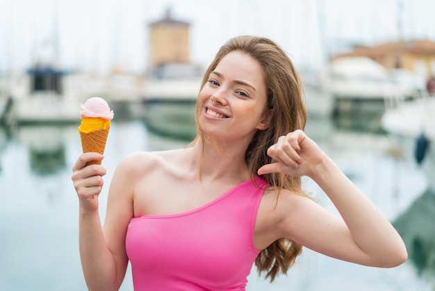 Junge rothaarige Frau mit einem Cornet-Eis im Freien, stolz und selbstzufrieden