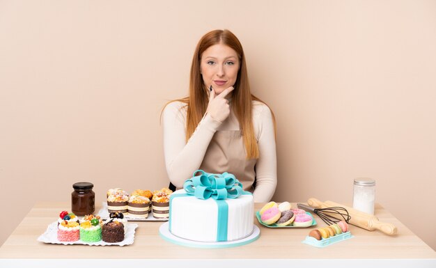 Junge rothaarige Frau mit einem großen Kuchen lachend