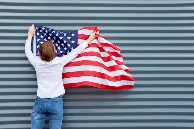 Junge rothaarige Frau mit rot gestrichenen Lippen, die mit der USA-Flagge stehen