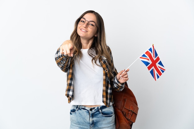 Junge rumänische Frau, die eine Flagge Großbritanniens auf weißer zeigender Front mit glücklichem Ausdruck hält