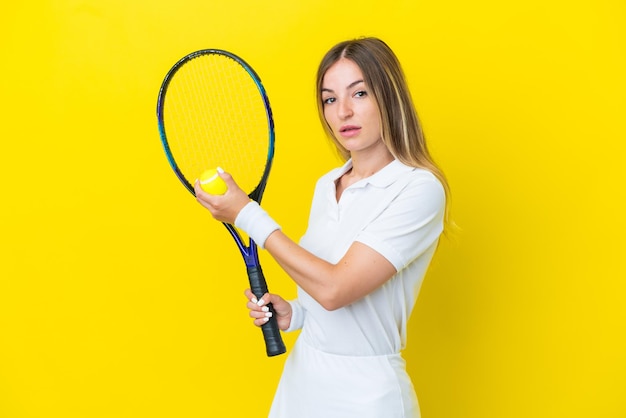 Junge rumänische Frau isoliert auf gelbem Hintergrund beim Tennisspielen