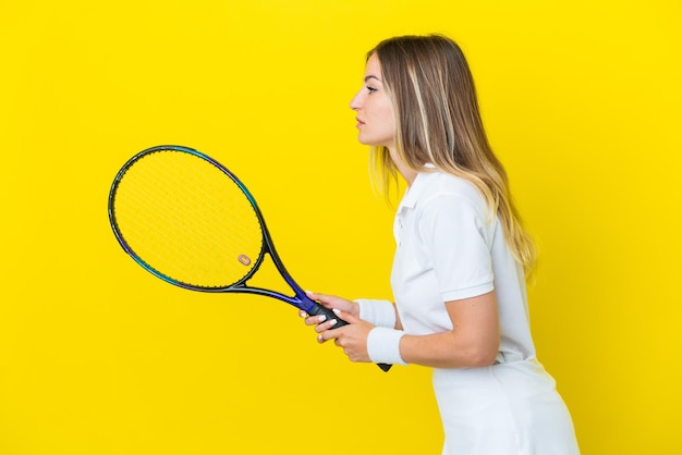 Junge rumänische Frau isoliert auf gelbem Hintergrund Tennis spielen