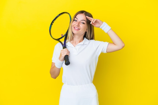 Junge rumänische Frau isoliert auf gelbem Hintergrund Tennis spielen