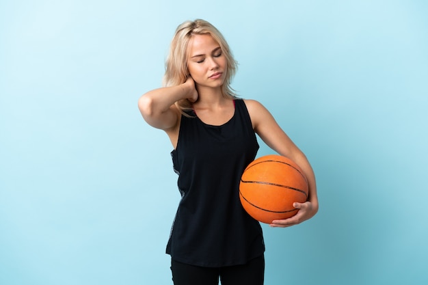 Junge russische Frau, die Basketball lokalisiert auf Blau mit Nackenschmerzen spielt