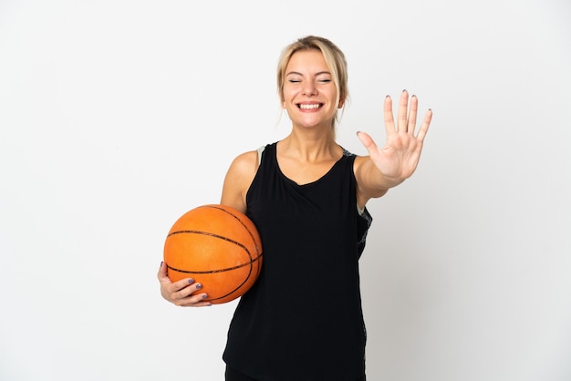 Junge russische Frau, die Basketball spielt, lokalisiert auf Weiß, das fünf mit den Fingern zählt