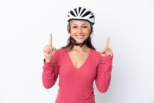 Junge russische Frau, die einen Fahrradhelm trägt, isoliert auf weißem Hintergrund, der auf eine großartige Idee zeigt
