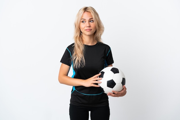Junge russische Frau, die Fußball spielt, der auf Weiß lokalisiert wird, das Zweifel macht, die Seite suchen